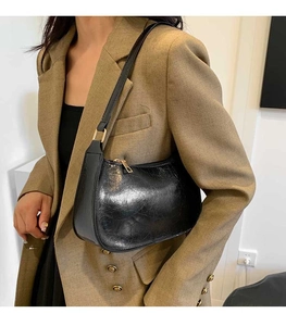 Detail of black oil-wax leather hobo bag with gold hardware worn on shoulder