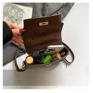 Internal storage of brown leather crossbody bag showing space for phone and cosmetics