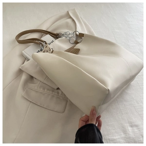 Detail of off-white tote bag with silver chain, brown handles and cat charm