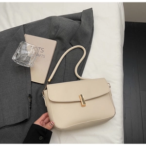 Detailed view of a cream leather crossbody bag with a gold metal clasp in a stylish setting