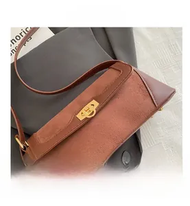 Detail of a brown leather and suede shoulder bag with a gold metal twist lock