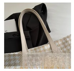Detail of herringbone weave fabric and reinforced faux leather handles on a tote bag