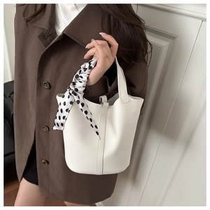 Close-up of white leather bucket bag with litchi grain and polka dot silk scarf