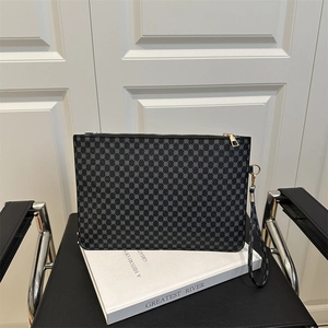 Elegante pochette grigio scuro con stampa geometrica e zip dorata su un libro