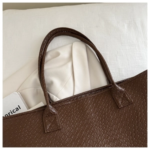 Close-up of dark brown woven texture tote bag handle stitching and premium PU material