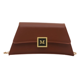 Brown leather trapezoid bag with gold M-logo buckle and chain strap on white background