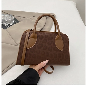 Dettaglio borsa vintage leopardata con manici in pelle marrone e tracolla rimovibile