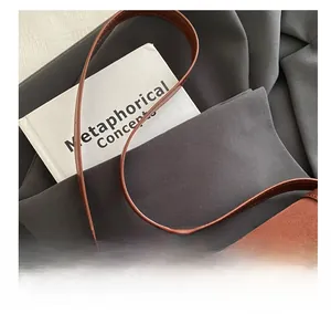 Detail of soft brown suede handbag featuring a premium gold twist lock and smooth handle