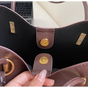 Detailed macro view of gold magnetic snap closure on deep brown leather tote bag