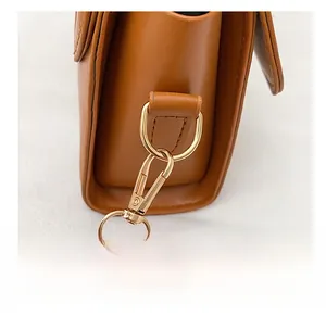 Gros plan du crochet en métal doré sur le sac à bandoulière en cuir marron