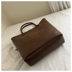 Close-up of dark brown woven texture detail on a large capacity leather tote bag