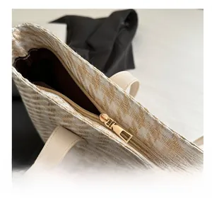 Detail of smooth metal zipper and herringbone weave texture on a woven tote bag