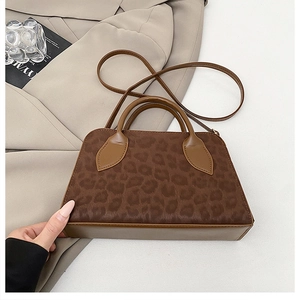 Dettaglio della borsa leopardata con manici in pelle marrone e tracolla lunga rimovibile