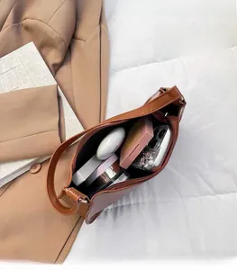 Top view showing large interior space of brown leather shoulder bag with personal items
