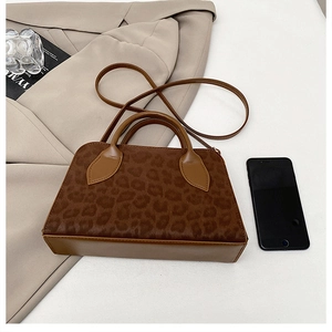 Detailed view of leopard print handbag with brown trim and slim shoulder strap