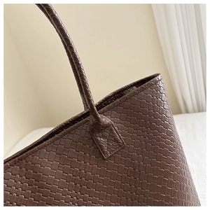 Detailed close-up of dark brown woven texture and stitched handle on a faux leather tote bag