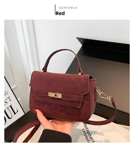 Close-up of wine red suede bag featuring a golden twist lock and thin shoulder strap detail