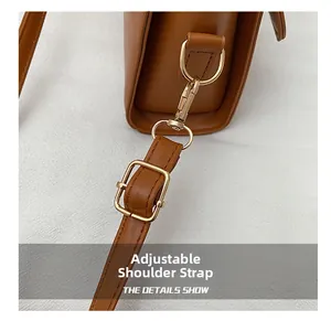 Détail de la bandoulière réglable en cuir marron avec des boucles en métal doré poli