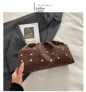 Dettaglio della borsa a mano leopardata marrone con rivetti dorati su una giacca grigia