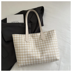 Detail of beige houndstooth tote bag featuring large capacity and leather shoulder straps