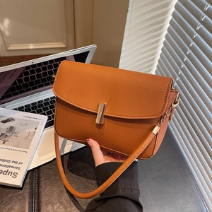 Brown rectangular leather shoulder bag with gold metal clasp in office setting