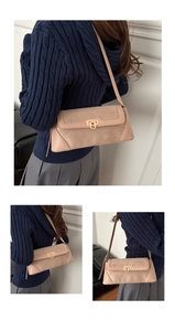 Close-up of beige shoulder bag with gold horseshoe buckle and textured leather stitching