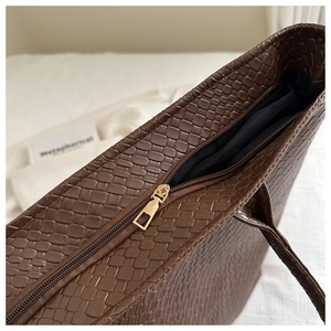 Detail of golden zipper and woven texture on a large dark brown tote bag