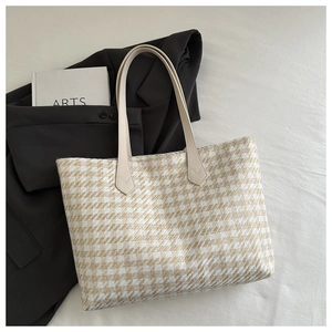 Flat lay of large houndstooth tote bag with cream leather handles and artsy book