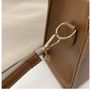 Dettaglio della borsa in pelle marrone con ganci in metallo dorato e cuciture rifinite