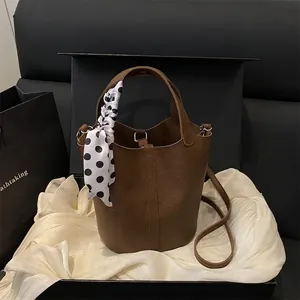 Sac seau en cuir marron avec foulard à pois présenté dans un coffret cadeau chic