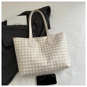 Detail of houndstooth weave texture on a large tote bag with slim cream leather handles