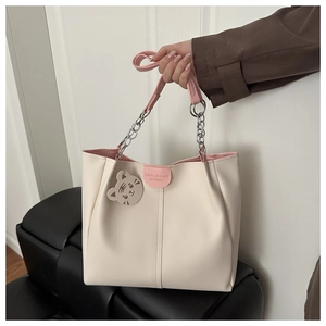 Detail of cream tote bag with pink handles, silver chain and cute cat leather charm