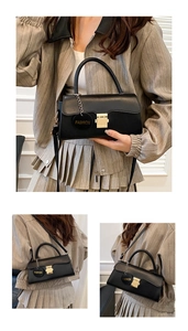Détail d'un sac bandoulière noir avec garniture dorée et breloque mode sur un modèle