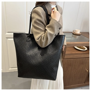 Close-up of black woven leather texture on a large capacity shoulder tote bag