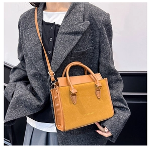 Primo piano di borsa a tracolla giallo senape abbinata a un blazer grigio in tweed