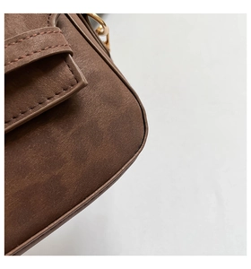 Detail of dark brown matte texture with golden metal hardware and fine stitching
