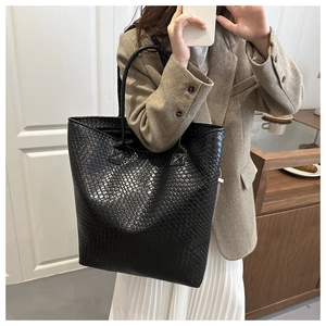 Detail of black woven leather tote bag with Intrecciato pattern for commute