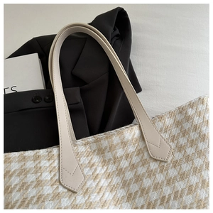 Close-up of herringbone fabric texture and cream leather handle on the tote bag
