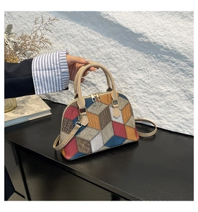 Macro detail of 3D geometric patchwork shell bag with golden hardware and beige handles