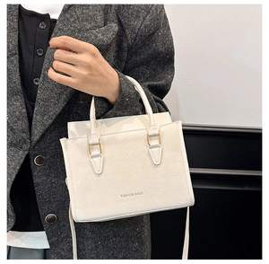 Dettaglio borsa a mano bianca in pelle PU con finiture dorate su giacca di tweed