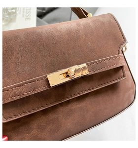 Detailed macro of golden metal twist lock and premium brown suede texture on a handbag