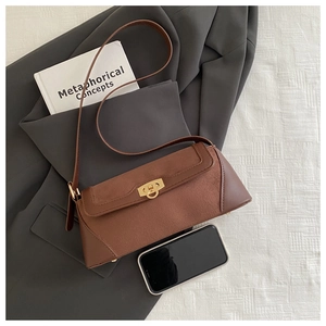 Detail showing the brown suede baguette bag size comparison with a smartphone and gold buckle