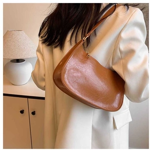 Detail of caramel brown vintage baguette bag with soft pleated leather texture and gold buckle