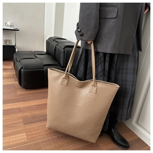 Close-up of beige tote bag showing high-quality crocodile pattern texture and handle detail