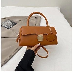 Détail d'un sac à bandoulière caramel avec fermoir doré et pendentif de mode