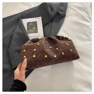 Dettaglio della borsa leopardata con rivetti dorati su uno sfondo minimalista