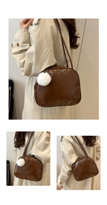 Detail of brown leather shoulder bag with a white fur charm and retro minimalist style