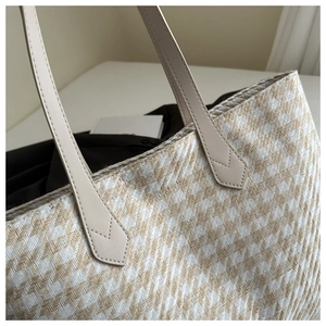 Detail of chevron woven texture and reinforced leather handle on the beige tote bag