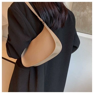 Close-up of a camel crescent underarm bag worn on the shoulder with a minimalist leather finish