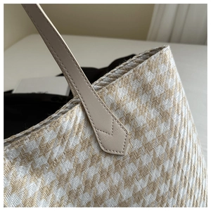 Detail of herringbone weave texture and premium leather handles on a beige tote bag